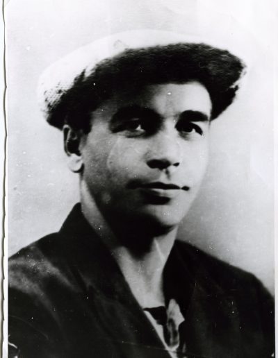 Photo of a young man wearing a cap and dark jacket, looking at the camera with a slight smile