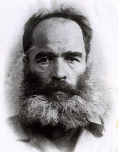 Portrait of an older man with a bushy salt and pepper beard looking at the camera with a serious expression